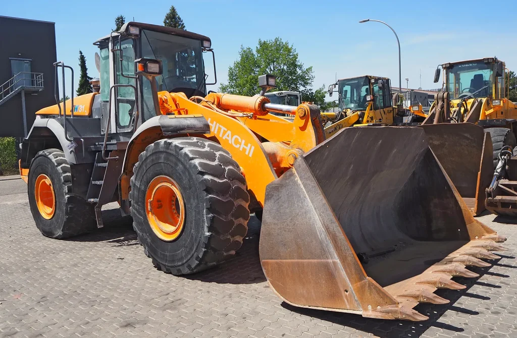Professional inspecting a used construction machine at an overseas site to verify its condition and avoid costly mistakes when purchasing.
