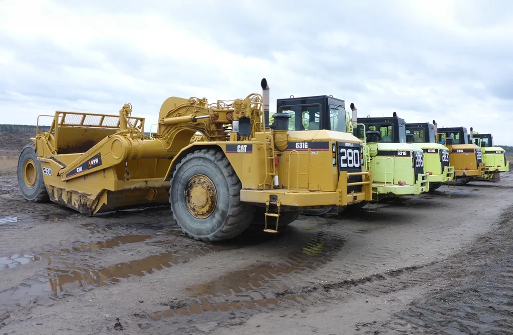 A construction site at dusk, showcasing a variety of machines such as loaders and graders